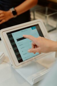 Close-up of a hand interacting with a tablet at a checkout counter, illustrating modern retail technology.